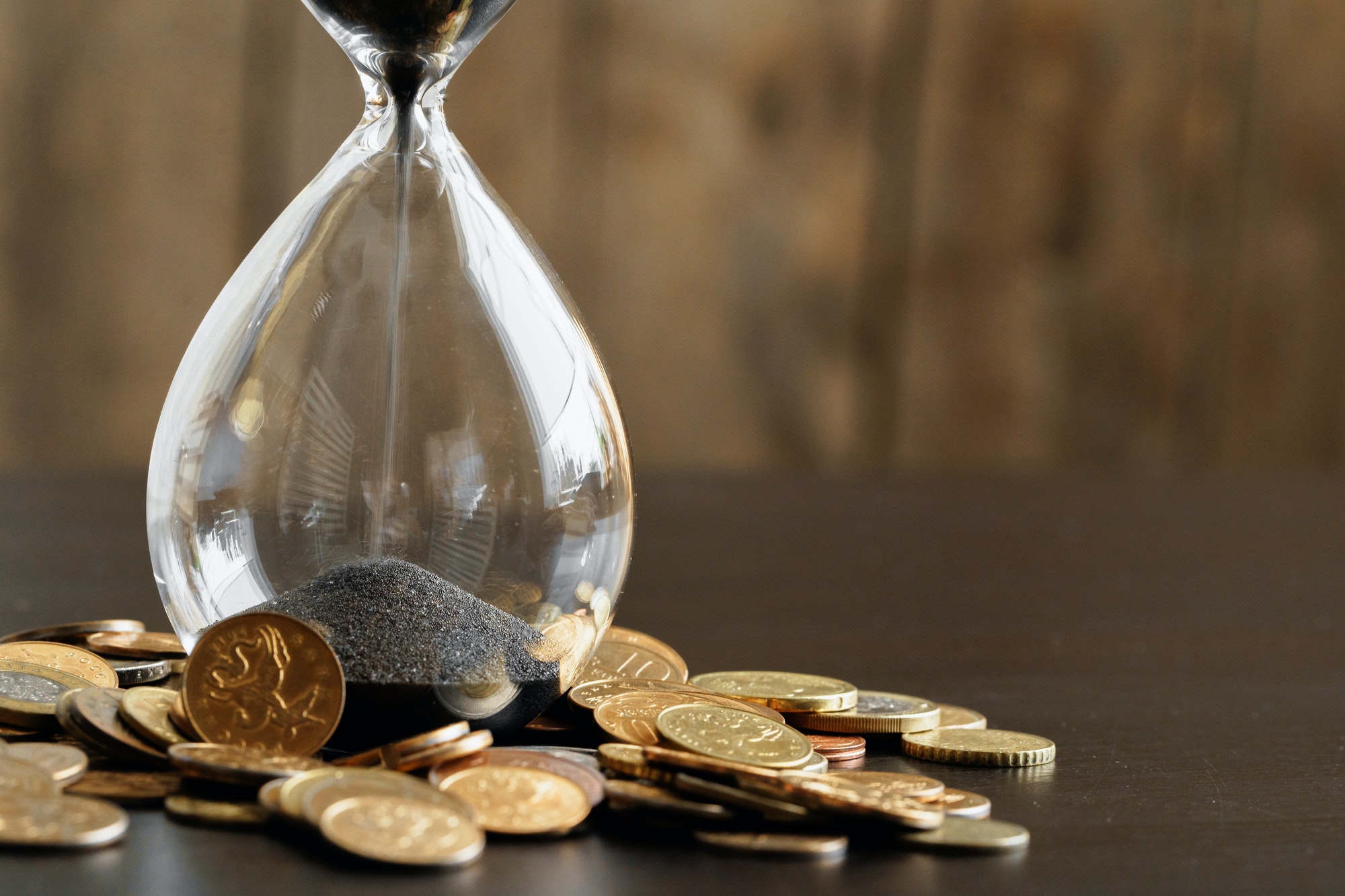 Time is money. Close up of hourglass with money coins